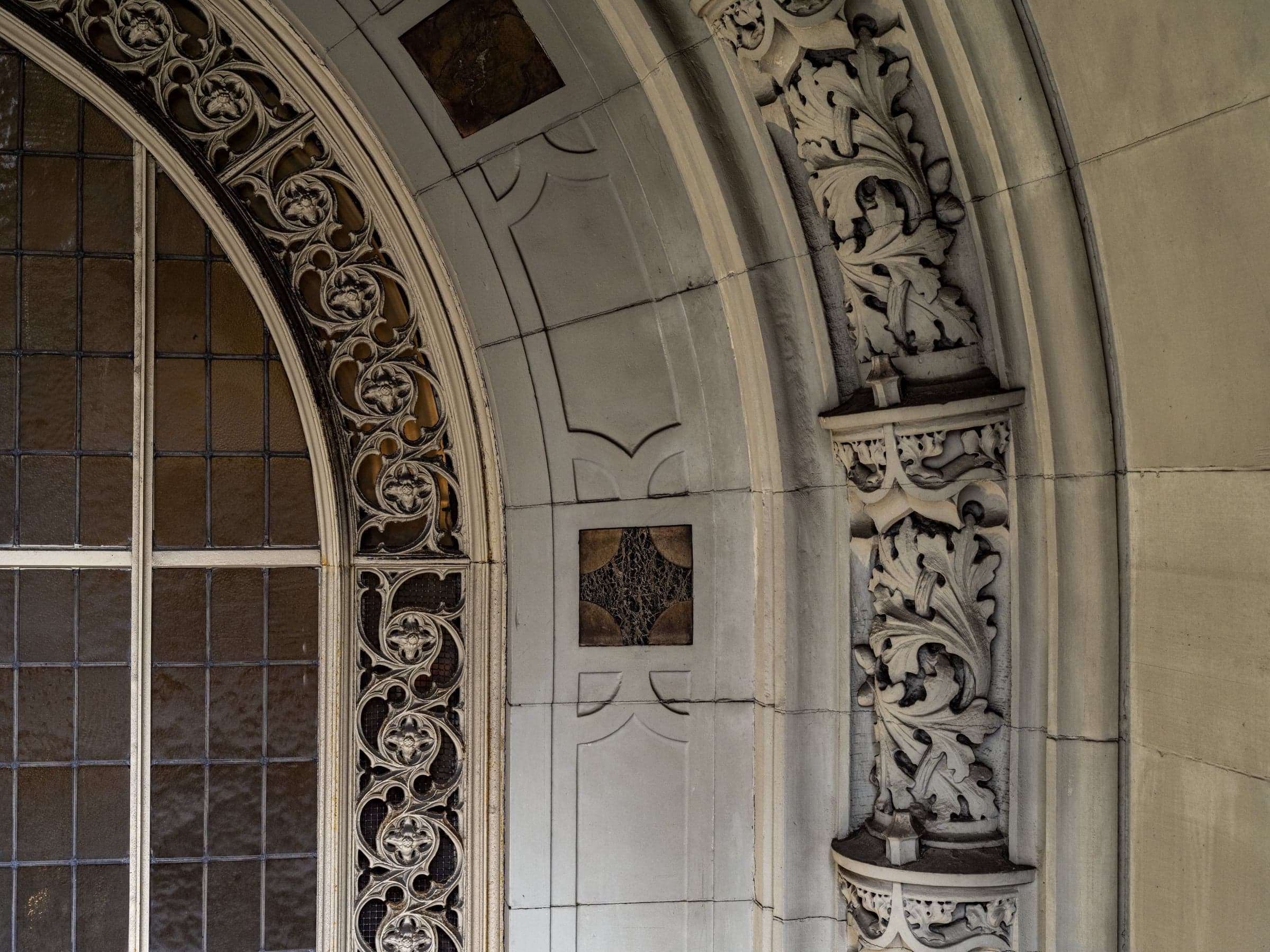 A conserved Gothic arched bay on the facade with foliate carving, seen up close from the scaffold.