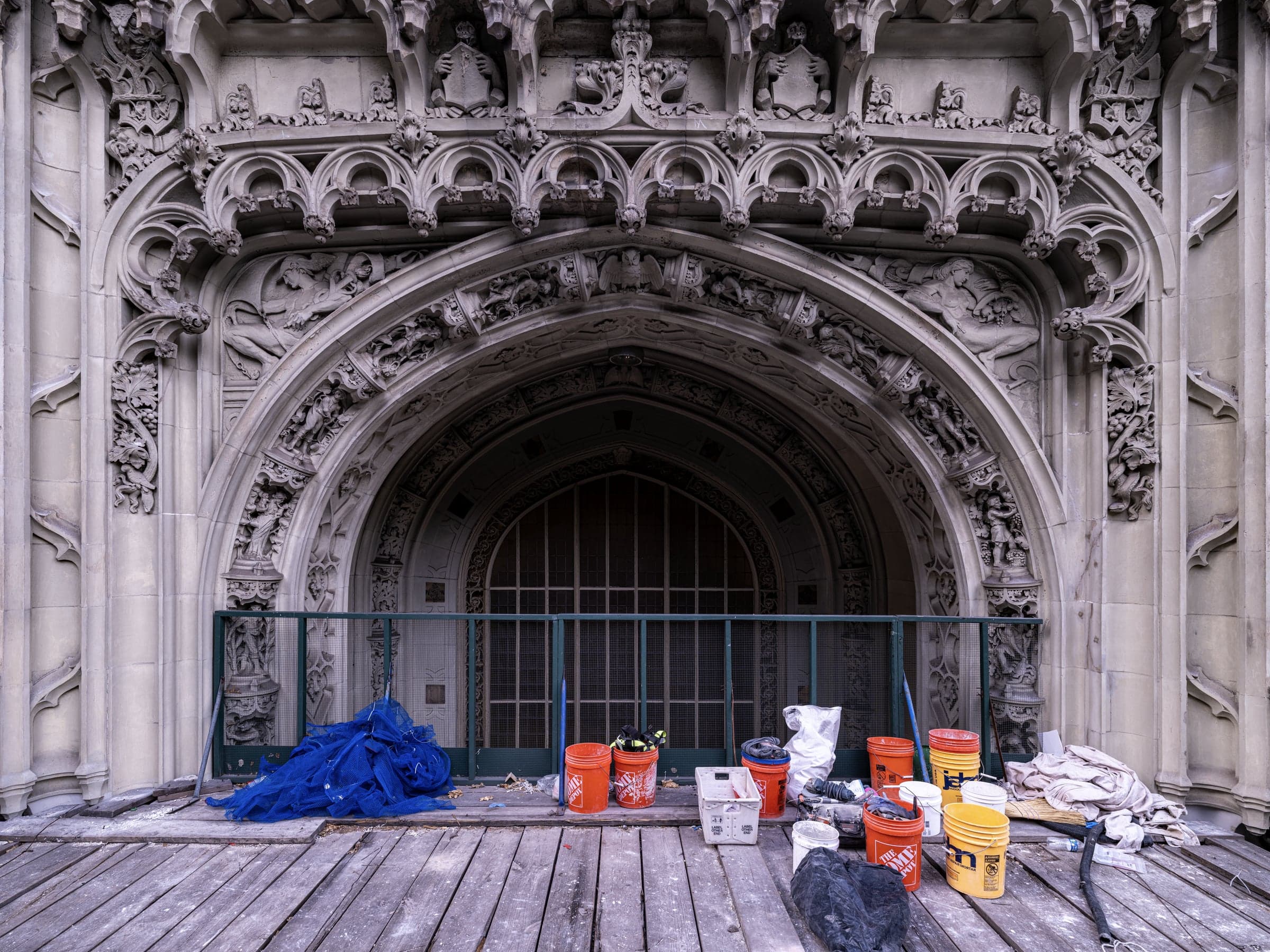 The Woolworth Building's main entrance arch seen from the scaffold deck, with restoration materials staged for work.